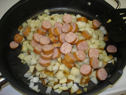 The sliced sausage added to the skillet.