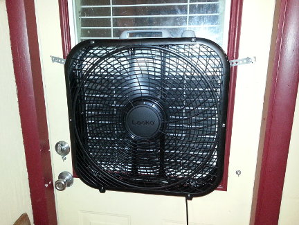 A fan installed in the window of the side door to the garage.