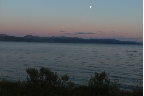 The moon over Yellowstone Lake with mountains in the background.